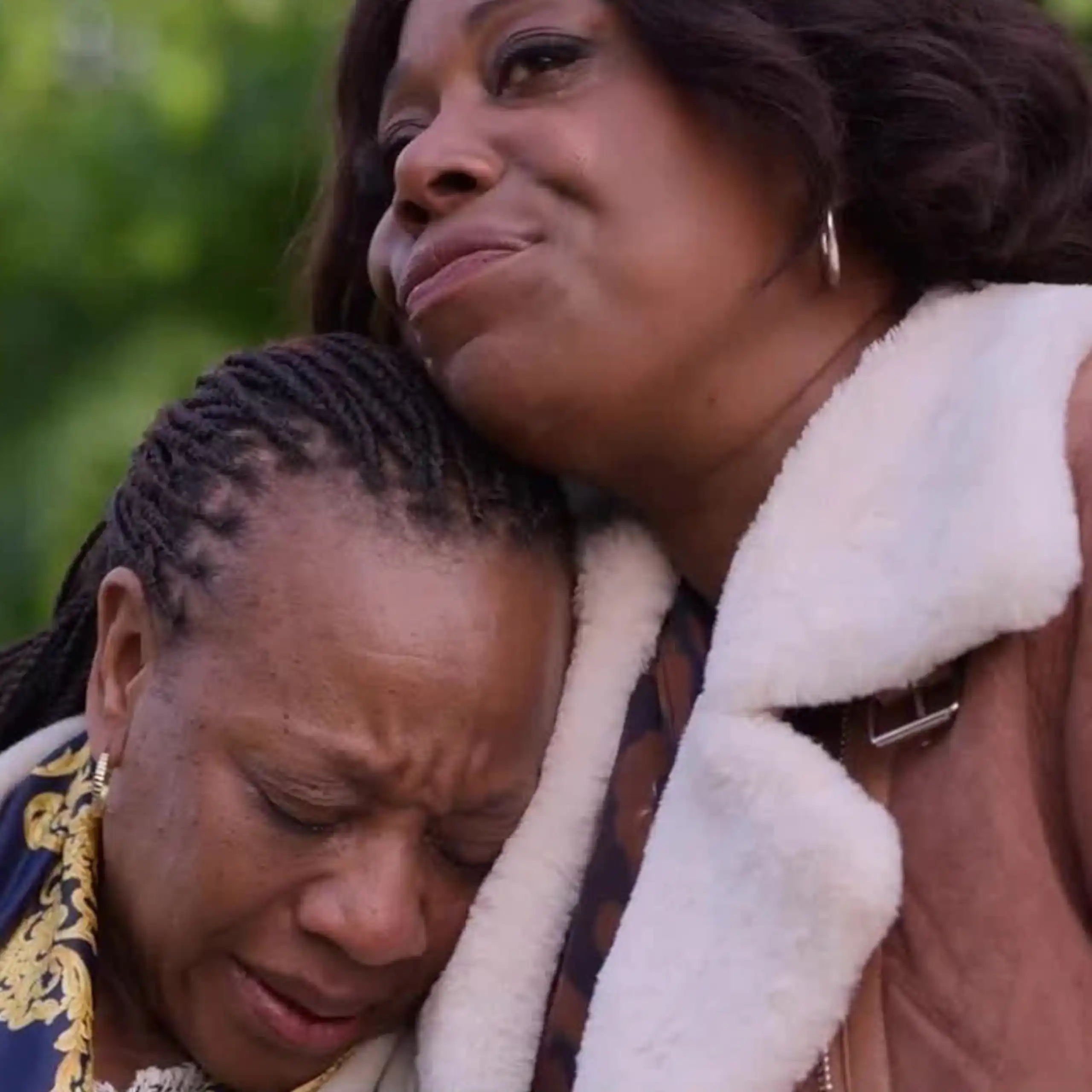 Two black women, one comforting the other is upset.
