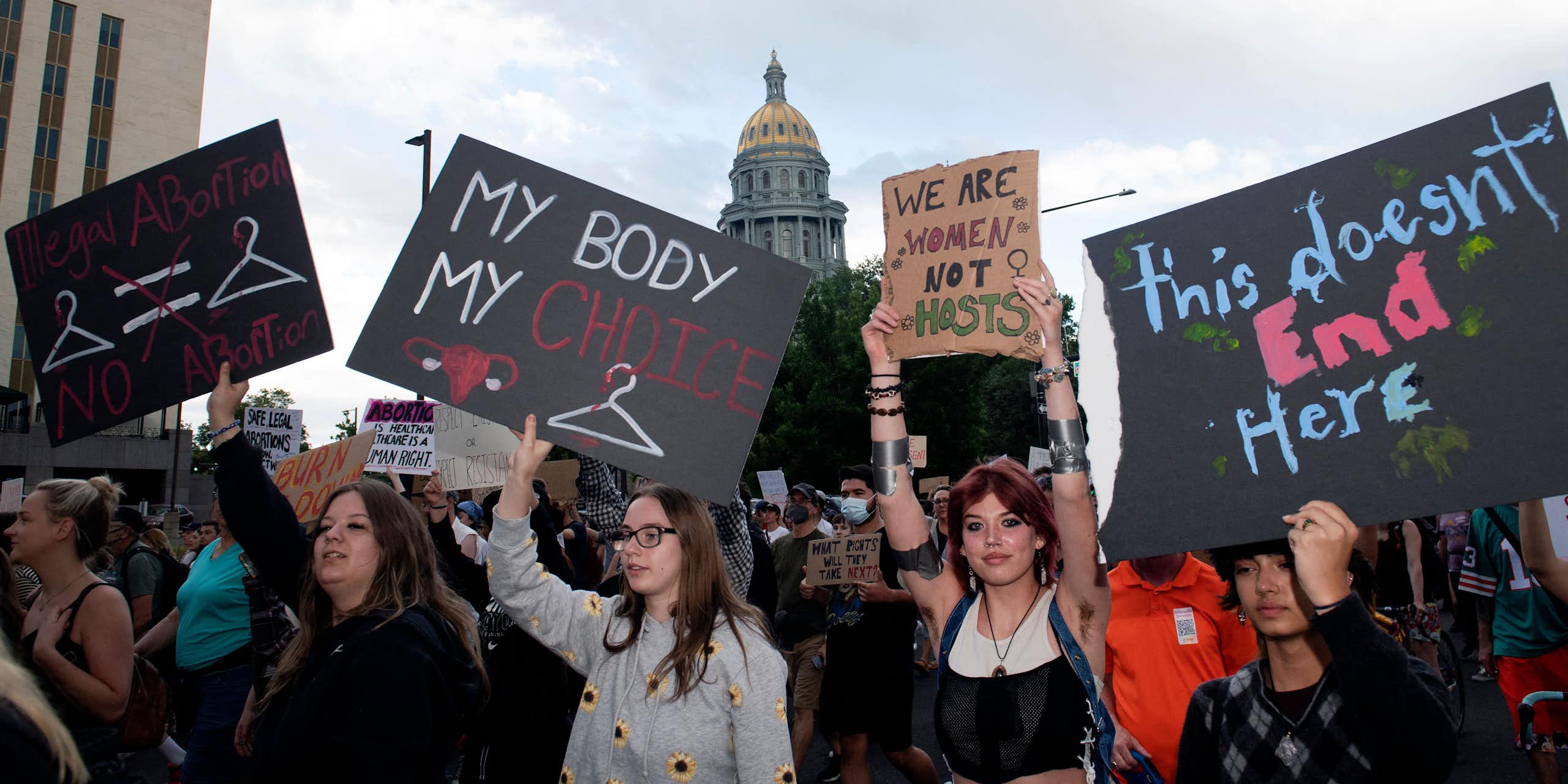 People protest in favor of abortion access, with a domed building in the background.