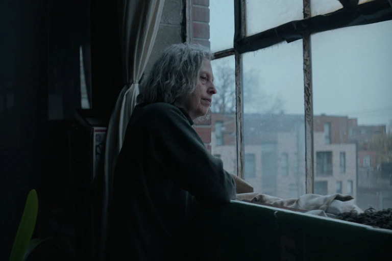 An elderly woman looks out of the window
