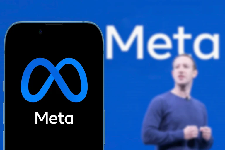 Mark Zuckerberg stands in front of a sign that says Meta