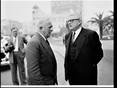 A black and white shot of two men in suits talking