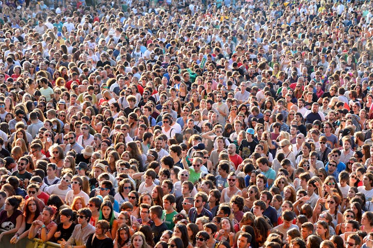 Large crowd of people standing in the sunshine.