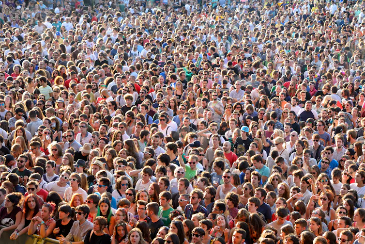 Large crowd of people standing in the sunshine.