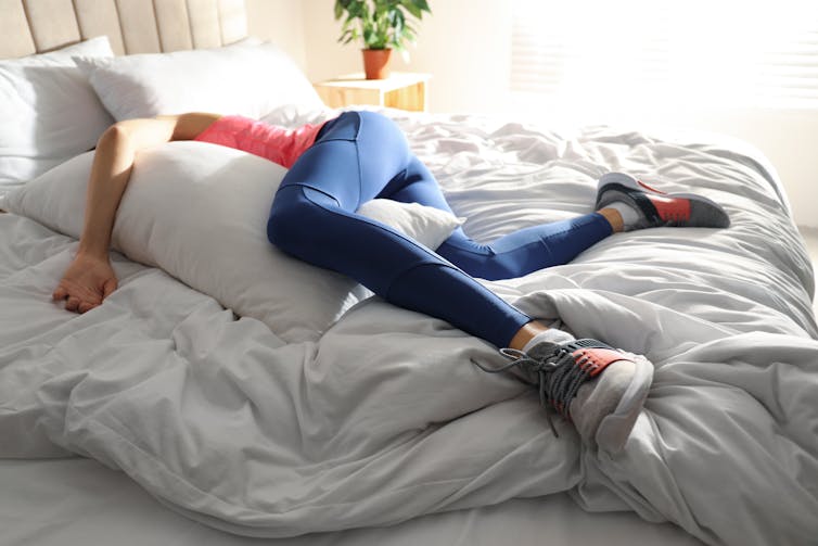 A woman in activewear is asleep on a bed