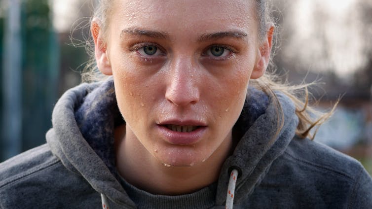 Woman wearing a hoodie, sweating.