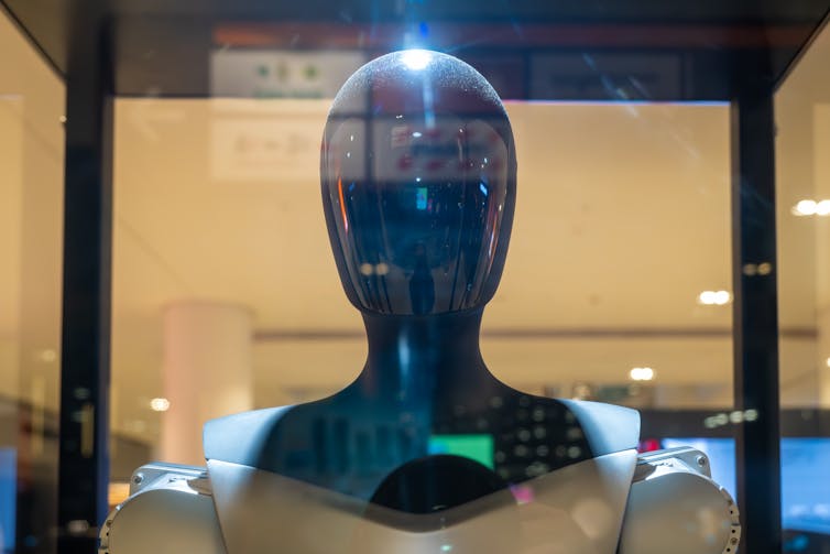 Black, shiny robot in a glass cabinet.