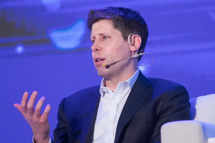 Mean wearing a suit speaking into a microphone on stage.