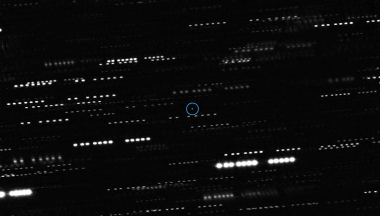 A series of bright streaks on a black background, with one light source circled in the centre.