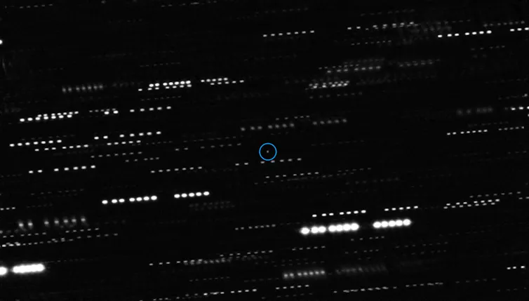 A series of bright streaks on a black background, with one light source circled in the centre.