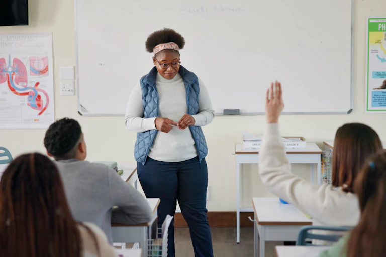 Teacher at front of class as pupil raises hand