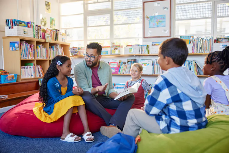 Teacher reading story to children in library