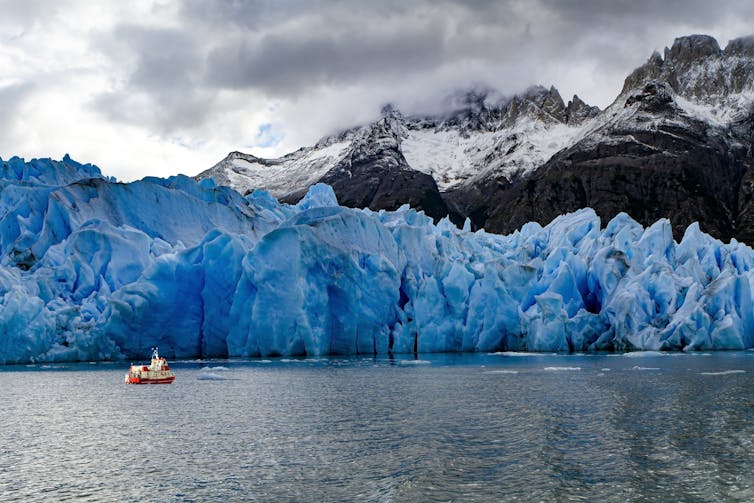 A blue glacier surrounded by water.