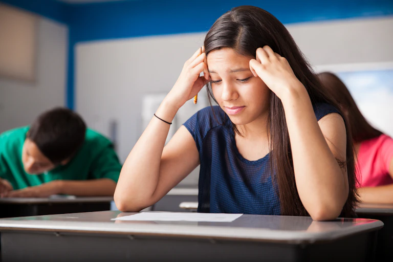 Une adolescente regarde sa copie dans une salle d'examens