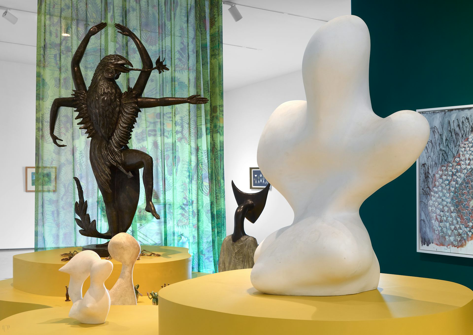 Sculptures surrounded by a colouful green curtain.