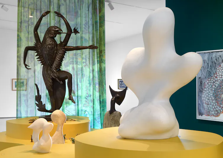 Sculptures surrounded by a colouful green curtain.