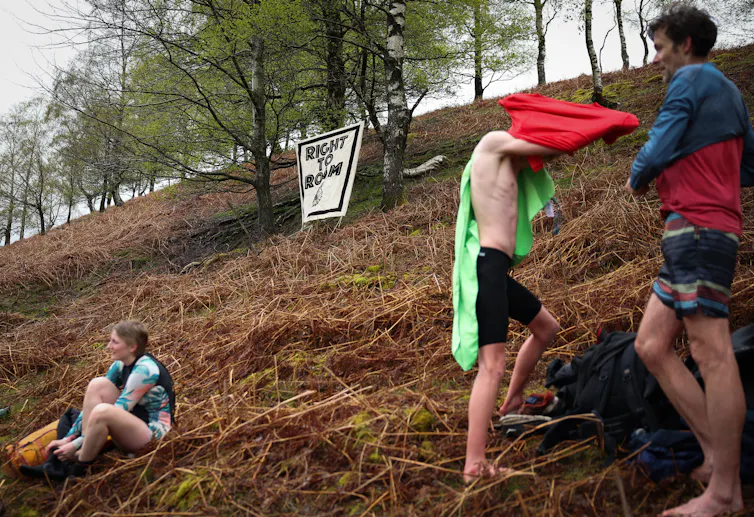 Young people on a hillside dry off from swimming.
