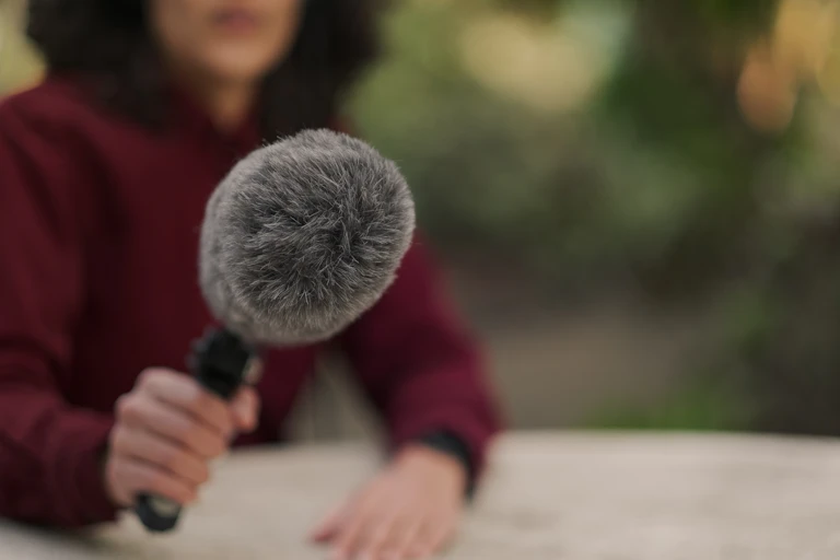 A person in a maroon shirt holding a microphone.