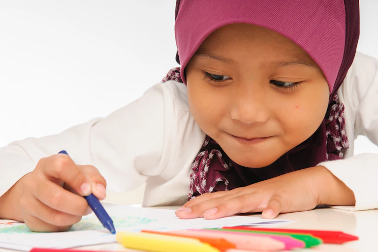 Little girl in headscaft uses colouring crayons