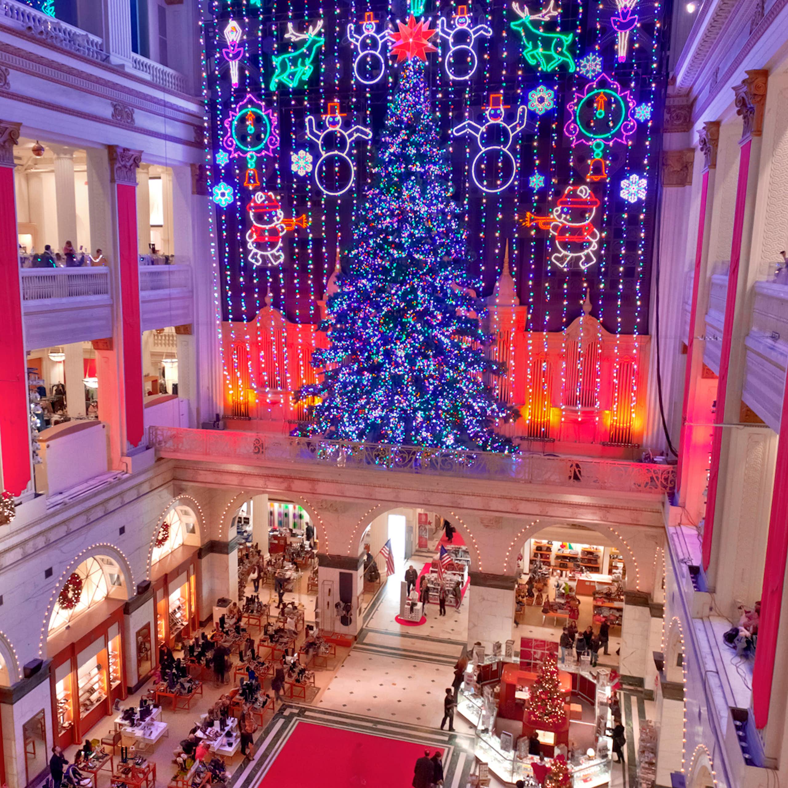 View from third-floor balcony of department store show and massive Christmas tree surrounded by lights depicting snowmen, reindeer and other holiday images