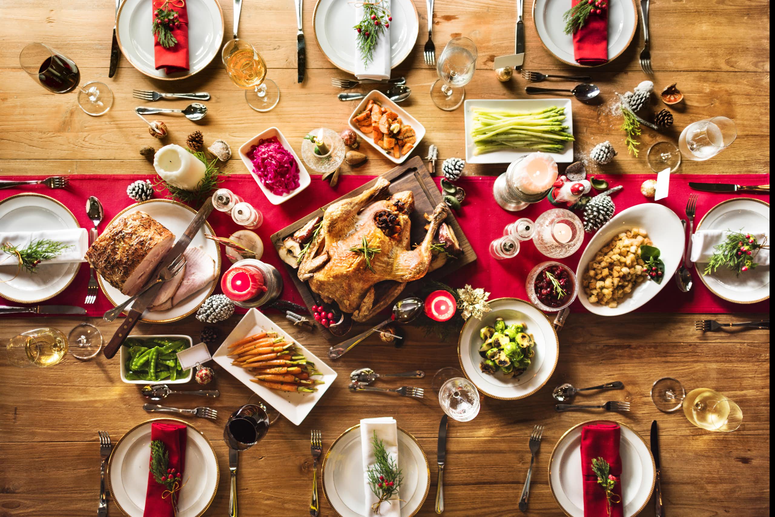Une table de Noël avec une volaille entourée de légumes.