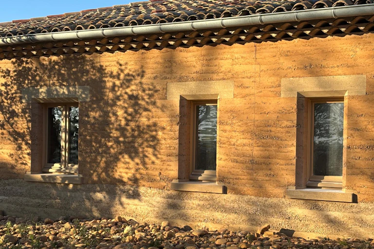close up of building with orange walls made of compacted earth