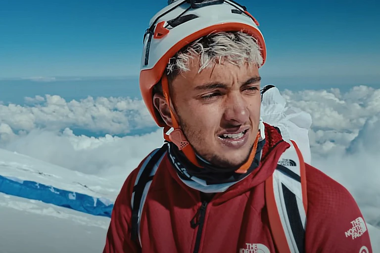 A man in mountaineering gear is at high altitude.