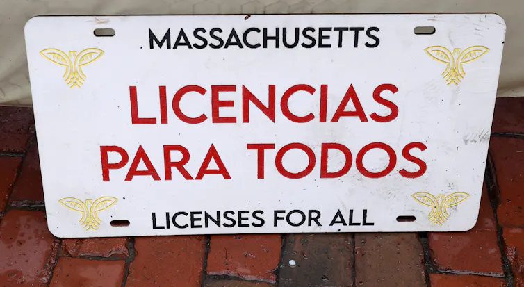 A white license plate reads 'Massachusetts: licenses for all' in both English and Spanish.