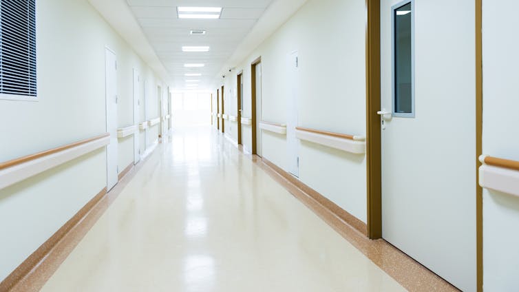 A white, empty hospital corridor with doors.