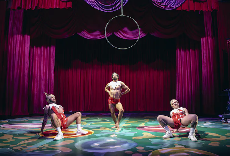 Three people on stage, in suggestive poses.