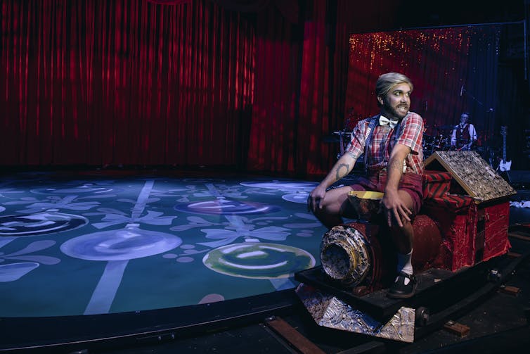 A man sits on a little train.