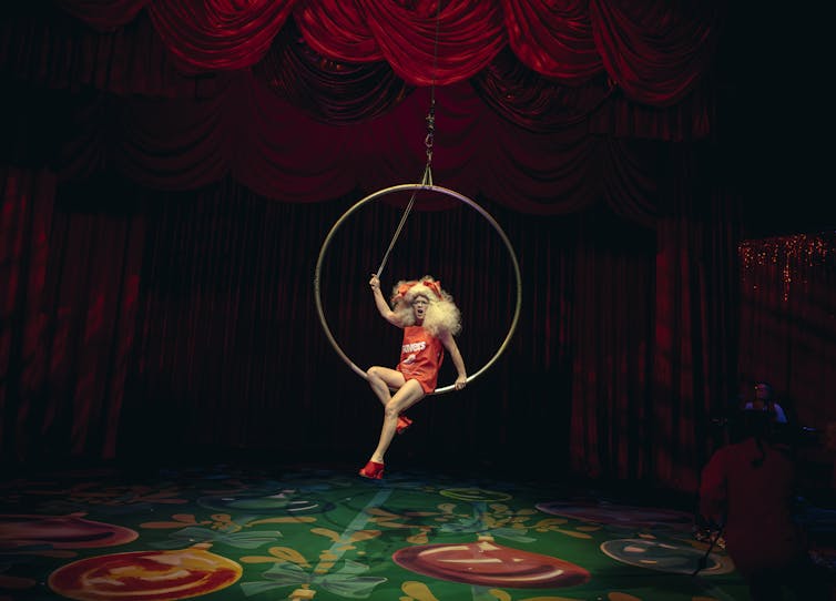 Someone sits in a hanging hoop.