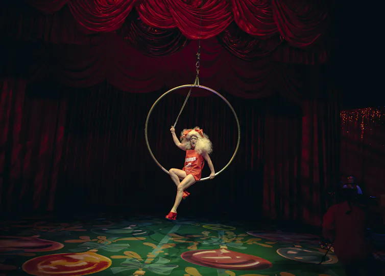 Someone sits in a hanging hoop.