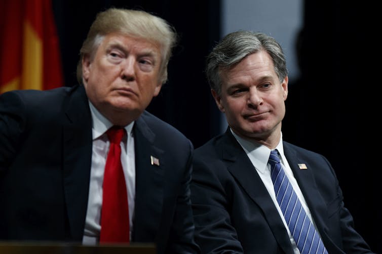 Two men in suits and ties sitting next to each other.