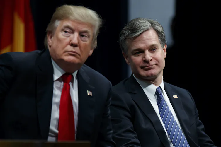 Two men in suits and ties sitting next to each other.
