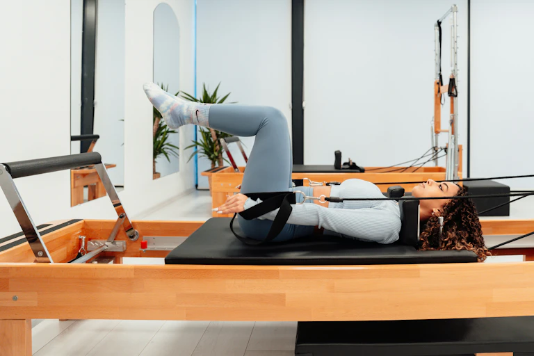 Woman bends in tabletop position on a reformer pilates machine