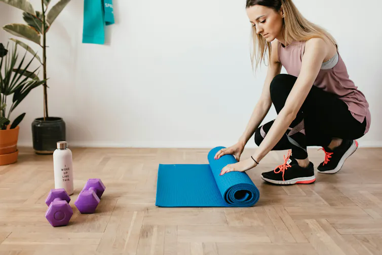 Woman rolls up exercise mat