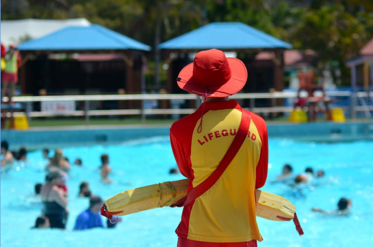 A lifeguard watches swimmers at a public pool.