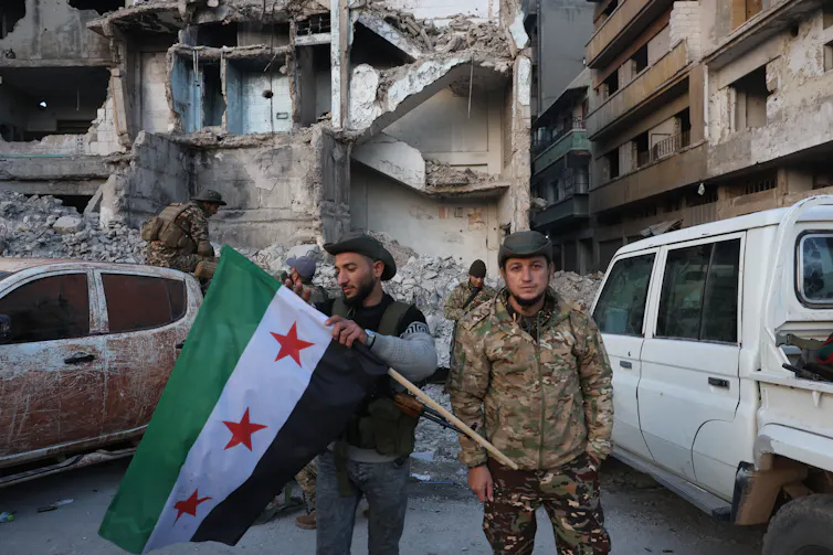 Syrian rebels pose with a Syrian opposition flag.