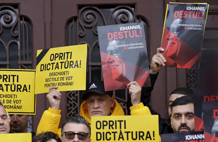Romanian protesters holding placards reading 'Stop The Dictatorship! Open The Polling Stations For Romanians!'.