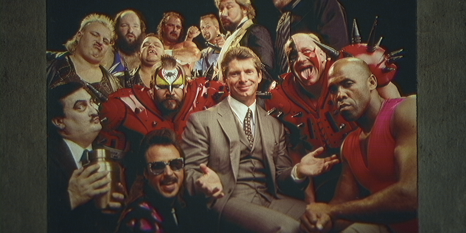 Vince McMahon in a suit surrounded by wrestlers