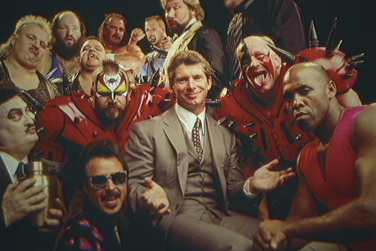 Vince McMahon in a suit surrounded by wrestlers