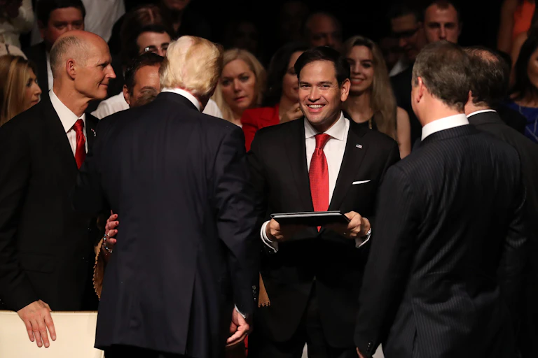 A man in a red tie smiles at the camera.