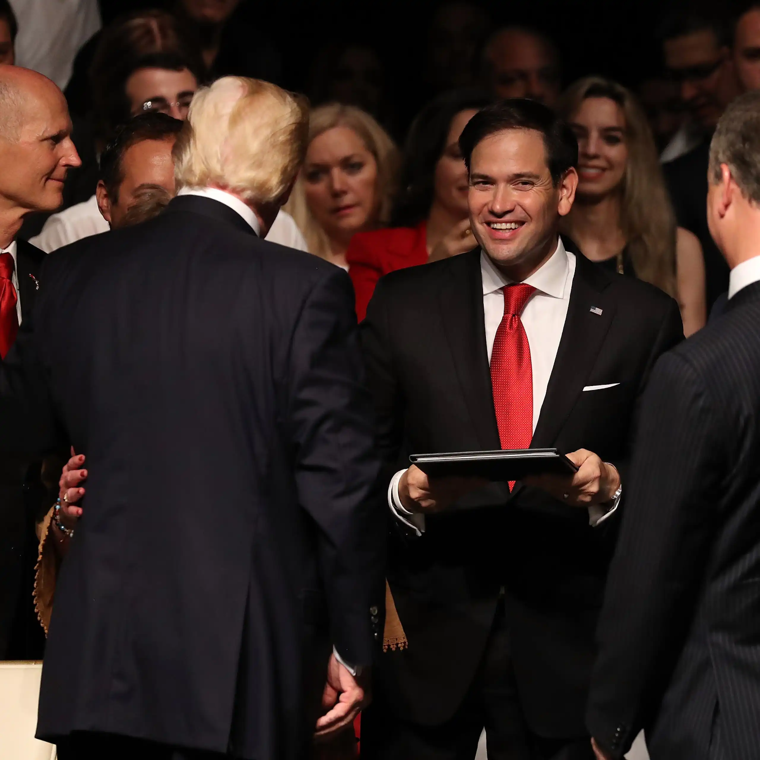 A man in a red tie smiles at the camera.