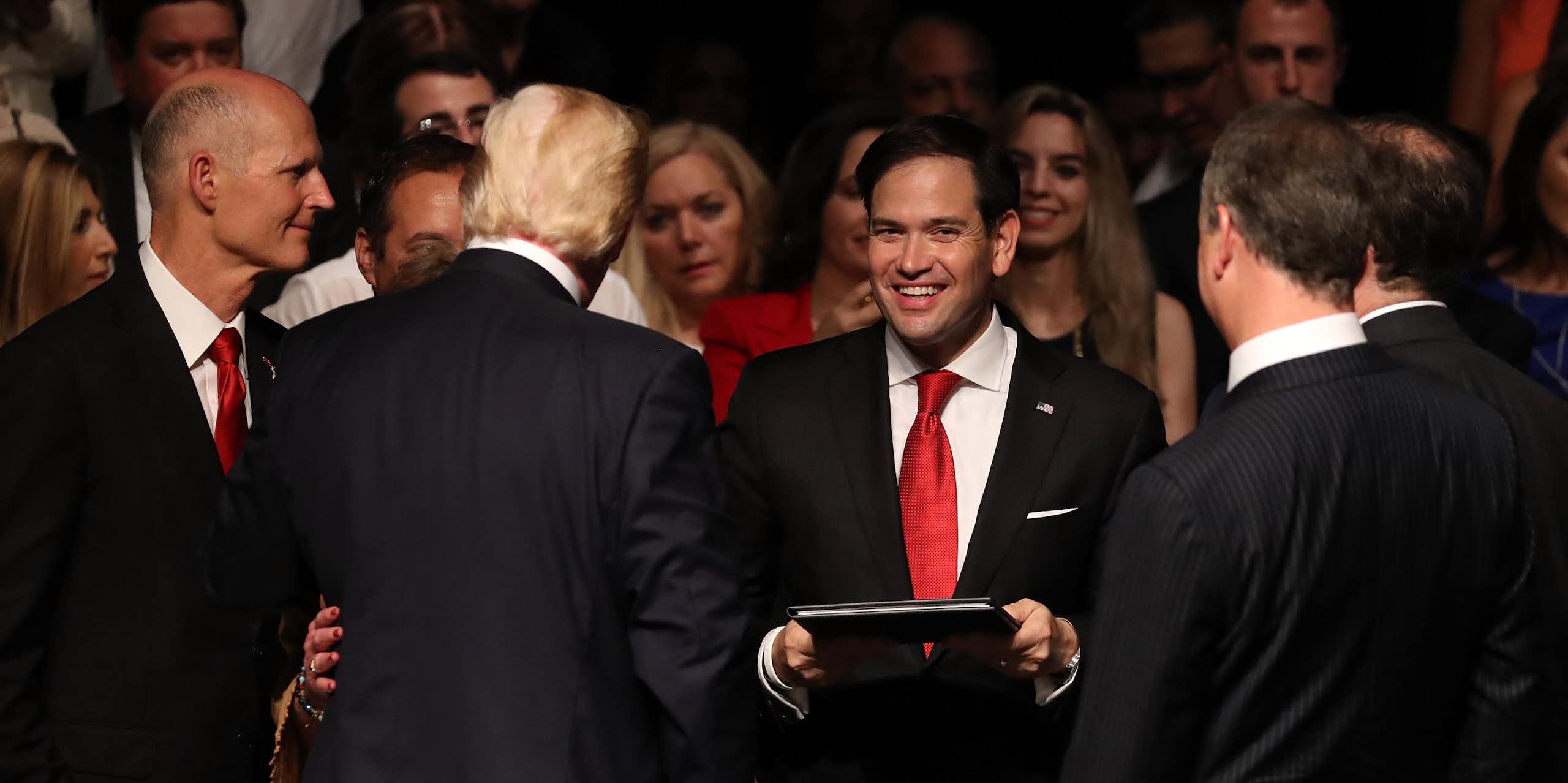 A man in a red tie smiles at the camera.