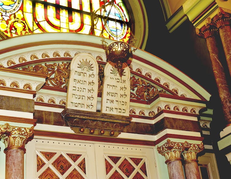 An ornately detailed section of a synagogue sanctuary, including a stained-glass window.