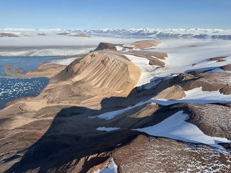 A snowy fjord is seen next to the ocean.