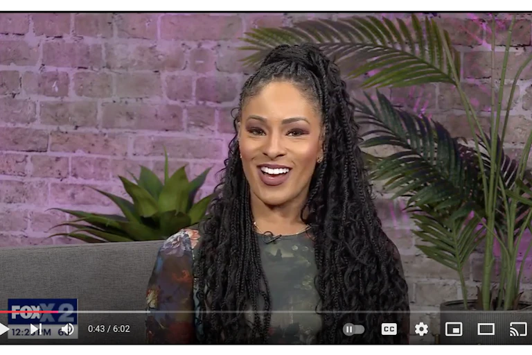 A pretty young Black woman smiles at viewers.