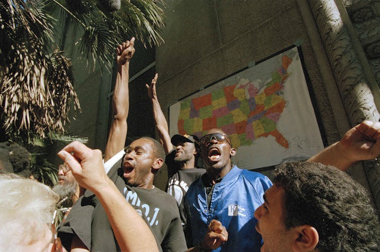 Black men cheer outside a courthouse.