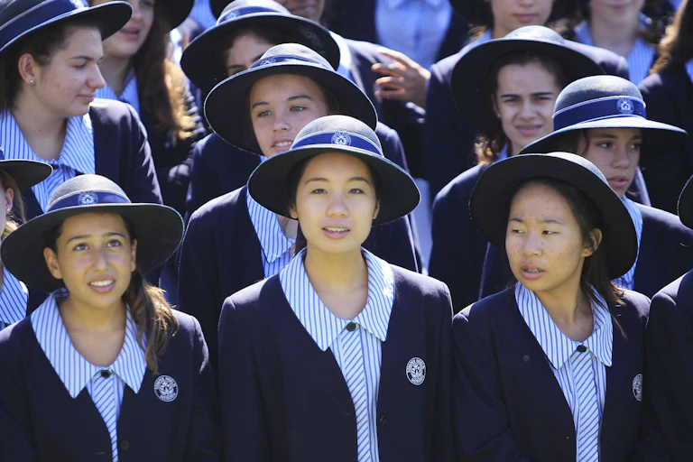 A group of private school students in hats and blazers.