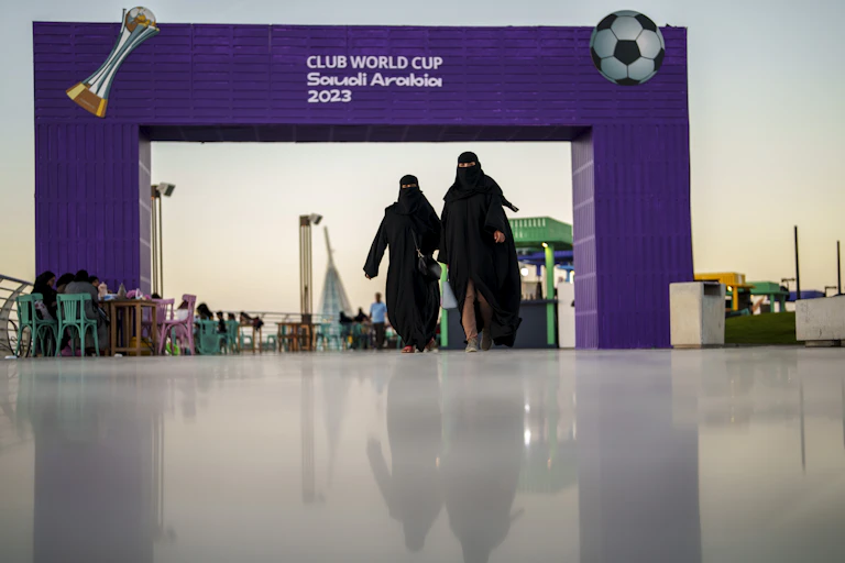 Women walk in front of a fan zone during the Soccer Club World Cup in Saudi Arabia, 2023.
